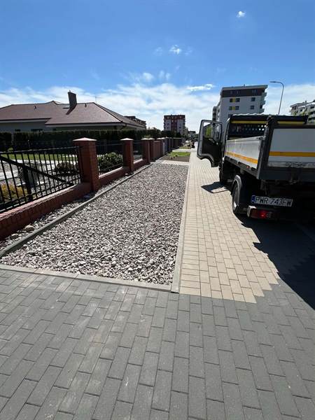 Pas kolorowego grysu wzdłuż ogrodzenia i chodnika